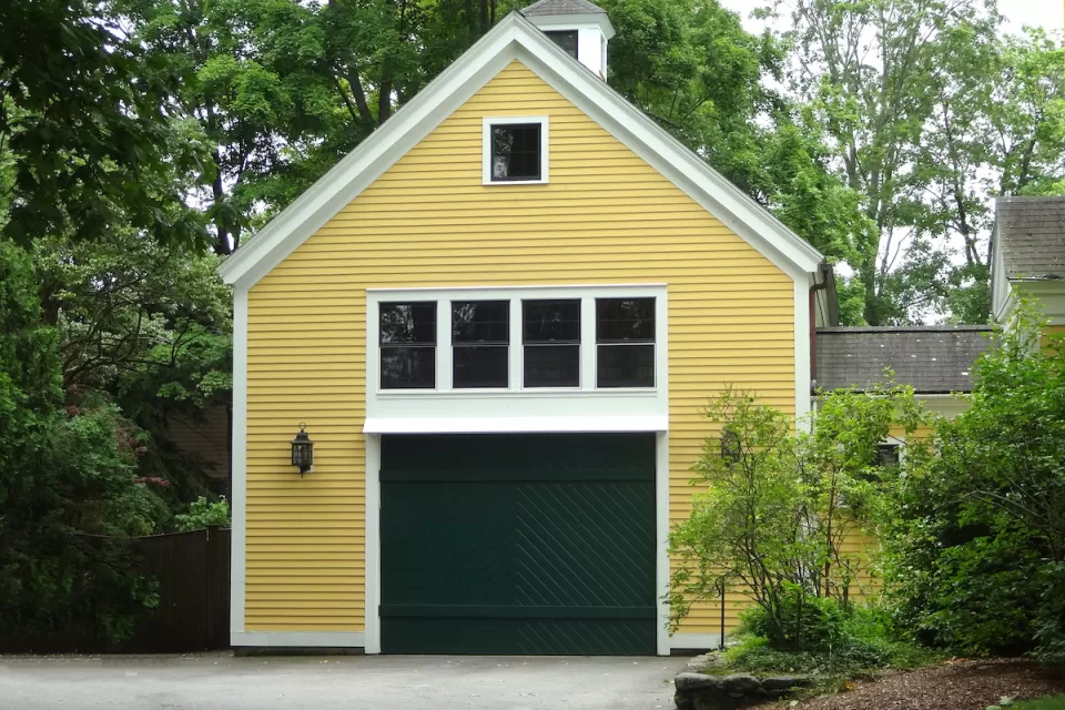 Yellow converted garage with green door and white-framed windows.